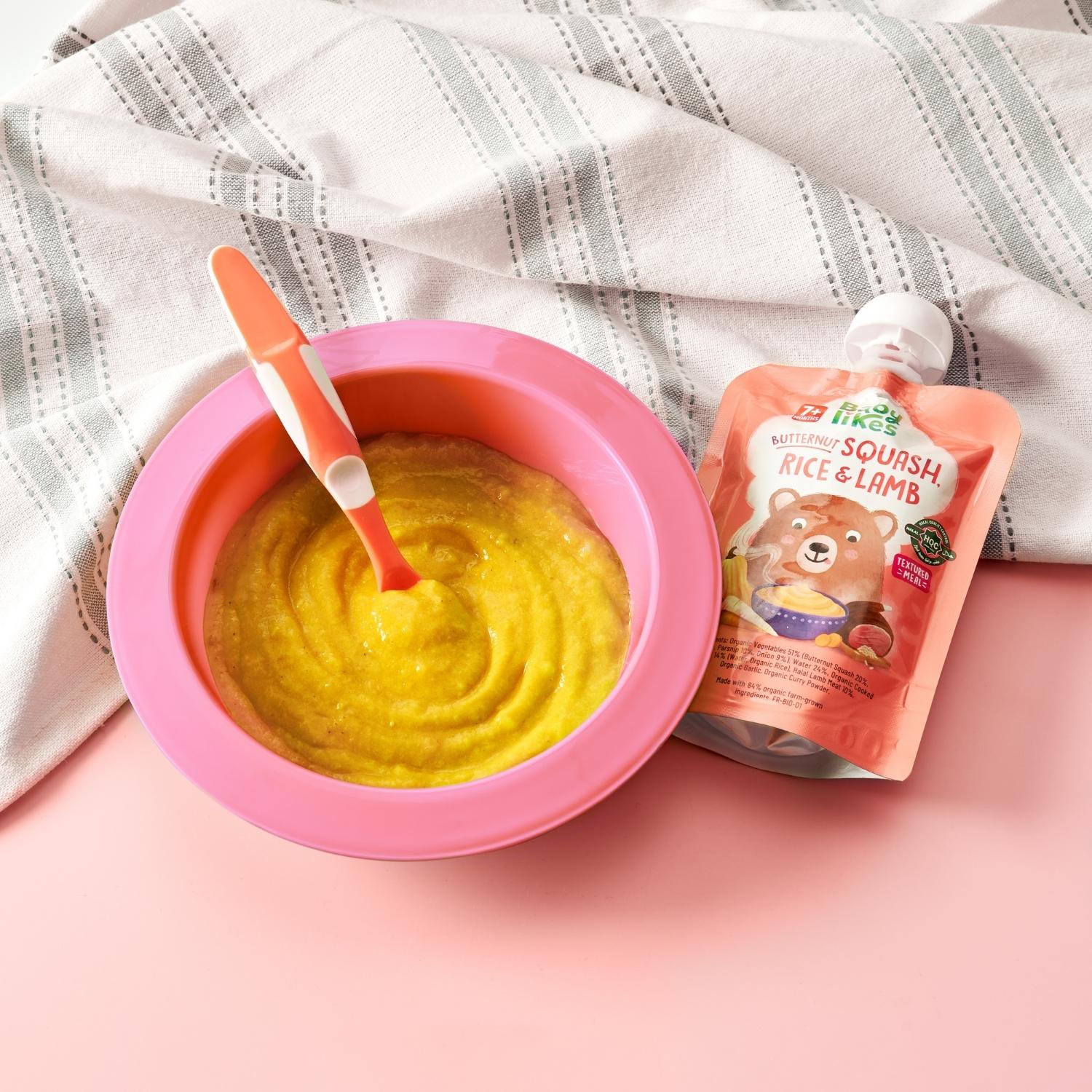 Bowl of Baby Likes Butternut Squash, Rice and Lamb 130g baby food beside its branded pouch, highlighting a wholesome, organic weaning meal for babies